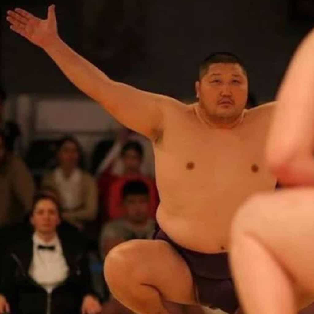 Sumo wrestler with arms raised during a match.