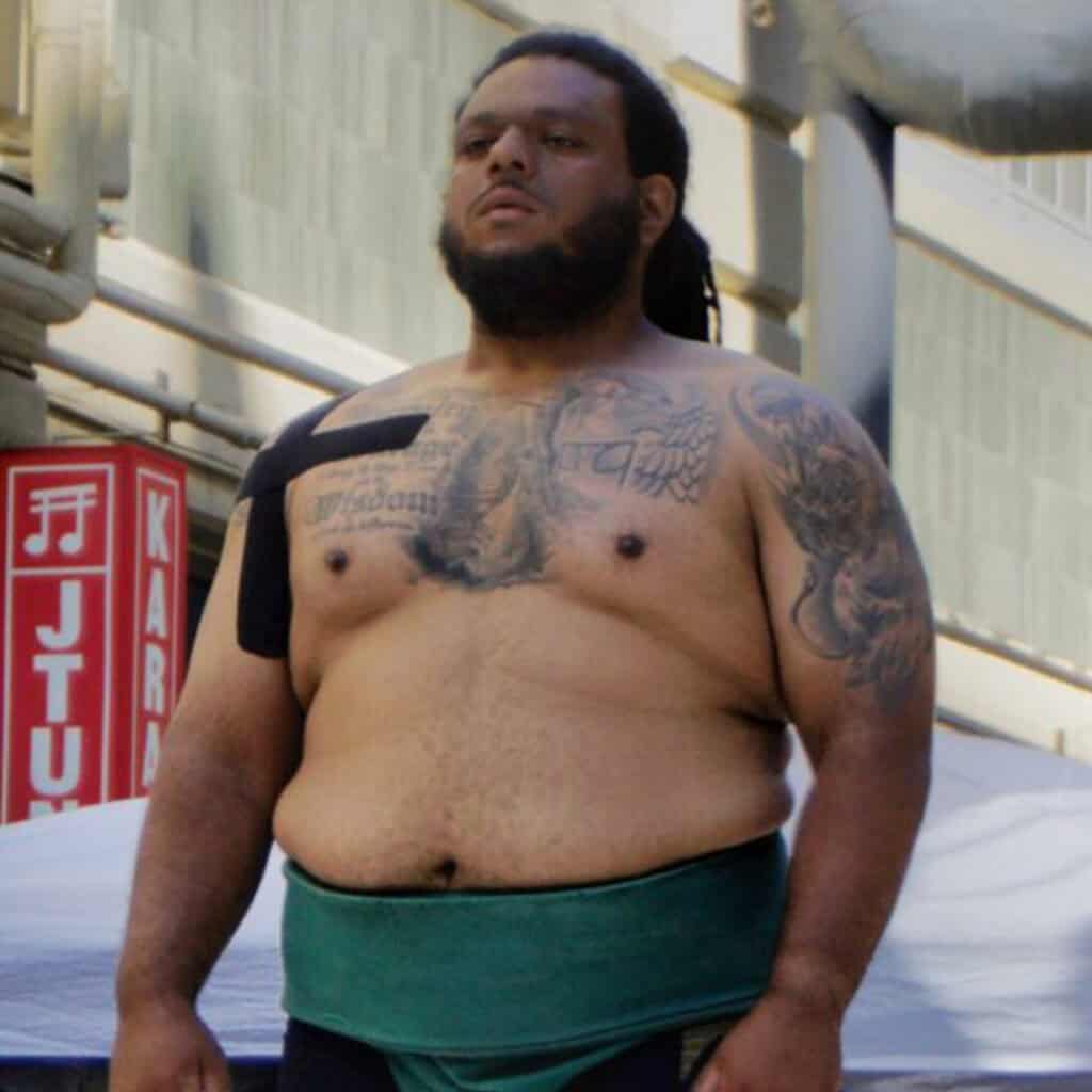 Sumo wrestler with tattoos and traditional mawashi.