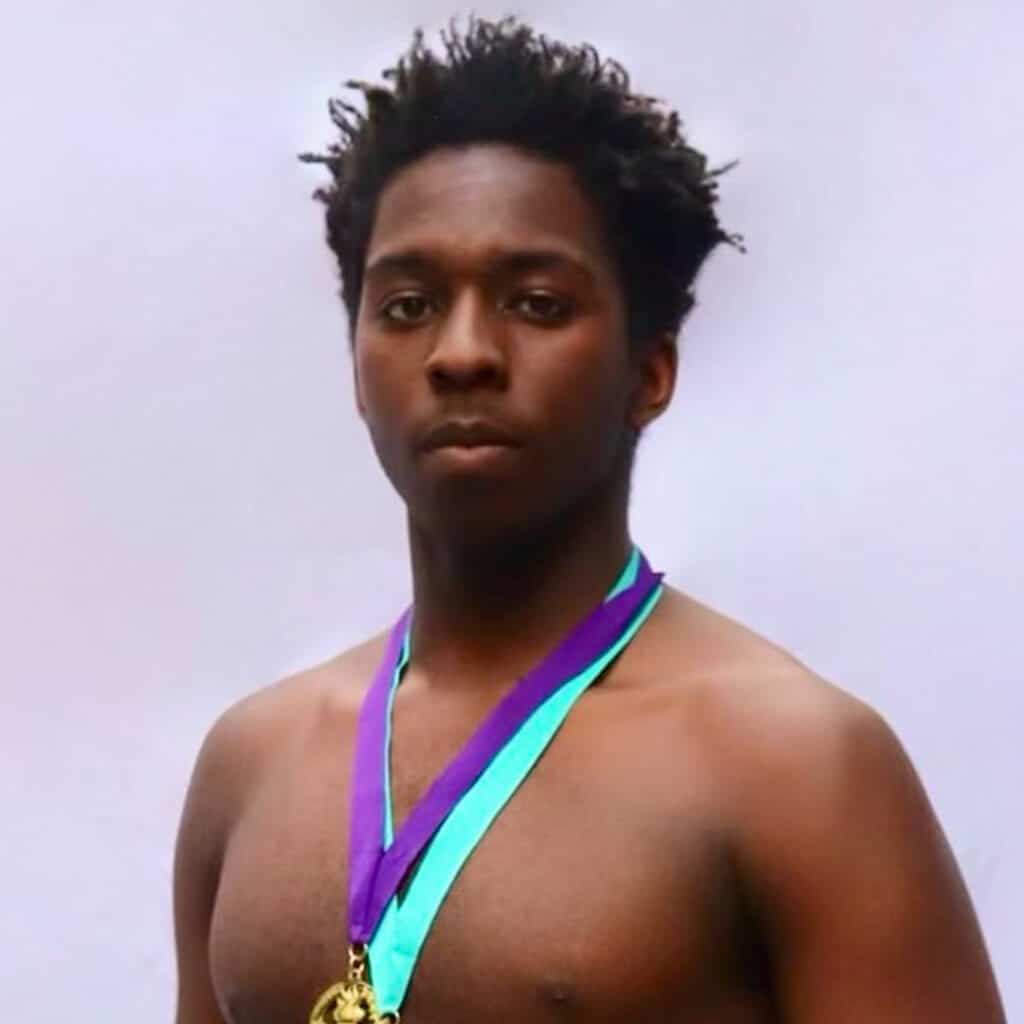 Young male sumo athlete with medals around neck.